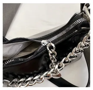 Détail de la fermeture éclair argentée et chaîne sur sac à main en cuir noir