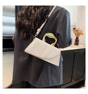 Detail of white crocodile texture leather bag with sculptural gold metal handle