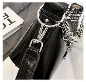 Gros plan du fermoir mousqueton argenté et de la chaîne sur un sac à main noir brillant