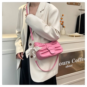 Détail d'un sac à bandoulière rose plissé avec foulard décoratif sur le mannequin