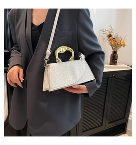 Close-up of white woven shoulder bag with gold metal handle on a grey blazer outfit