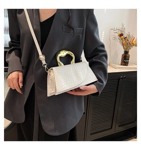Detail view of white embossed texture bag featuring unique gold metal handle and strap