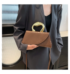 Close-up of brown crocodile pattern handbag with circular gold hollow metal handle