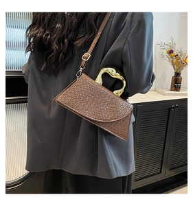 Detail of a dark brown woven crossbody bag featuring a unique gold heart-shaped metal handle