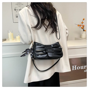 Détail d'un sac à bandoulière plissé noir avec foulard en soie et boucle sur un modèle