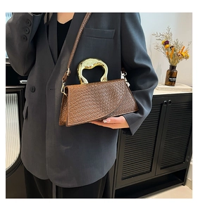 Detailed view of brown woven texture bag with a semi-circle gold metal handle