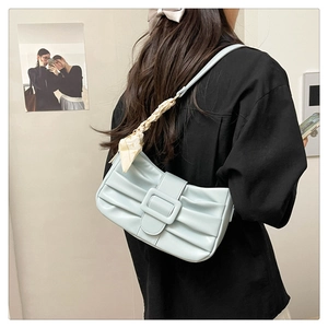 Détail d'un sac sous le bras plissé bleu clair avec foulard en soie porté par un mannequin