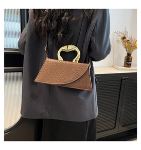 Detail view of brown crocodile texture leather bag with unique golden metal handle