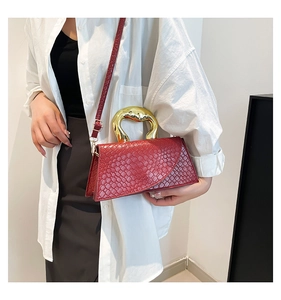 Detail of reddish-brown woven texture bag with unique gold handle worn by model