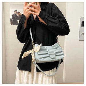 Détail du sac à bandoulière plissé bleu clair avec un accessoire foulard en soie au passant