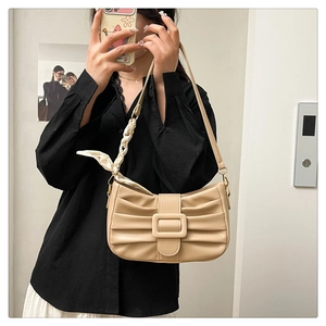 Détail du sac beige plissé avec boucle carrée et foulard en soie sur la bandoulière