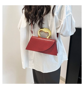 Detailed view of red croc-embossed leather bag with unique gold-tone metal handle