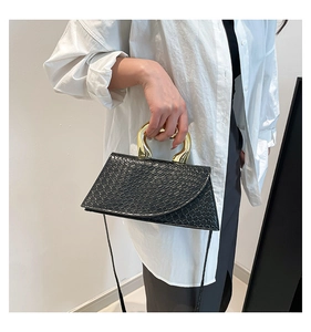 Detail of black faux crocodile leather bag with a bold gold curved metal handle
