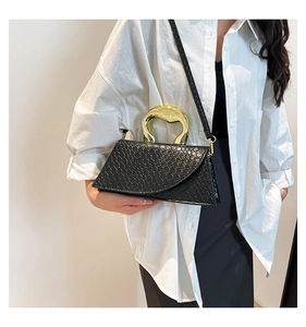 Detail of black crocodile texture bag featuring a unique gold irregular metal handle