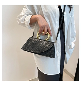 Close-up of black crocodile embossed handbag with unique gold irregular metal handle