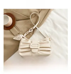 Détail du sac sous l'aisselle plissé crème avec motif nœud et accessoire foulard en soie