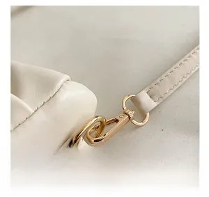 Vue détaillée des ferrures dorées et des coutures sur un sac à bandoulière beige froncé