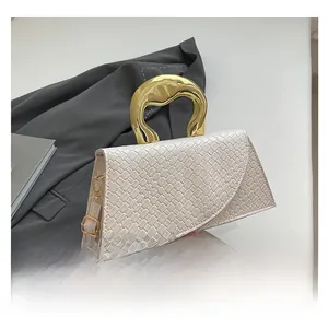 Detail of white woven texture crossbody bag with unique irregular gold metal handle