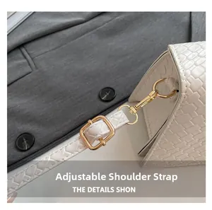 Close-up of adjustable white crocodile embossed shoulder strap with gold metal buckle