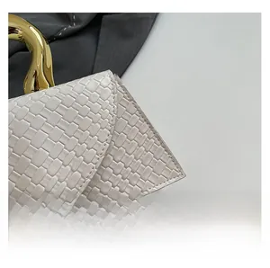Detailed close-up of white woven leather texture with a gold metal handle on handbag