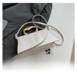Close-up of white embossed leather handbag with unique gold metal handle and mobile phone size reference