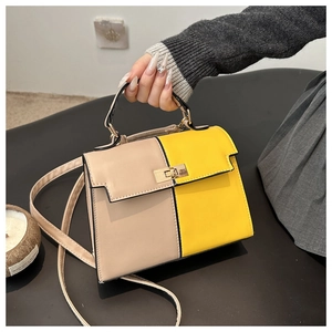 Detail view of the contrast color stitching and metal twist lock on Kelly handbag