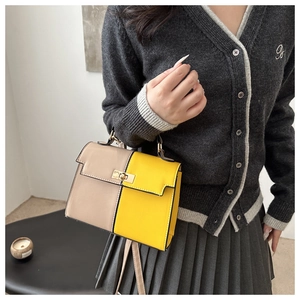 Détail d'un sac à main beige et jaune avec un fermoir rotatif doré sur le rabat avant