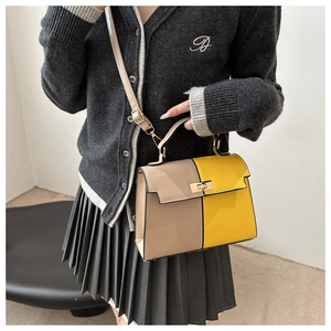 Detail of color-block Kelly bag with gold buckle on a crossbody shoulder strap