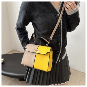 Detail view of contrast color patchwork handbag with gold rotary lock and top handle