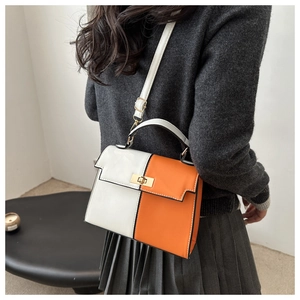 Detail of two-tone orange and white Kelly bag with gold lock and adjustable strap
