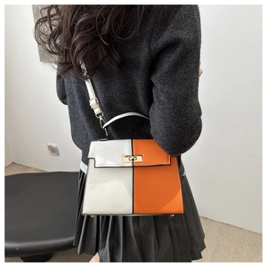 Detail of two-tone orange and white Kelly bag with silver metal lock and top handle