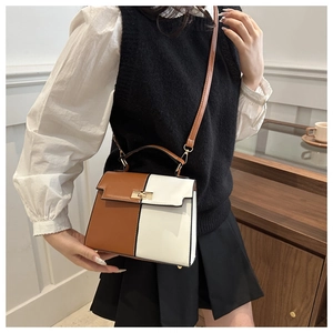 Detail of a color-block trapezoid handbag featuring a brown and cream PU leather design