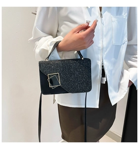 Detailed view of black sequin handbag with gold geometric buckle and metallic texture