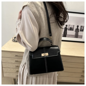 Détail du sac à main noir avec coutures blanches contrastées et fermoir doré rotatif