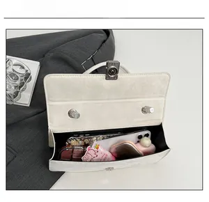 Detail view of the cream shoulder bag interior showing daily essentials and metal clasp