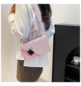 Pink crossbody bag with glitter texture and gold chain strap shown on model's shoulder