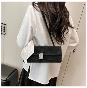 Detail of black velvet shoulder bag with silver diamond buckle and white heart print scarf