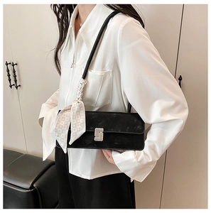 Detail of black velvet baguette bag with rhinestone buckle and stylish silk scarf handle