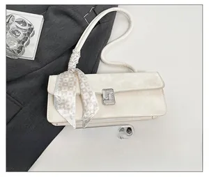 Detail showing cream baguette bag size compared to mobile phone and silk scarf decor