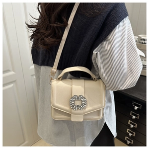 Detail of elegant beige leather handbag with rhinestone square buckle and adjustable strap