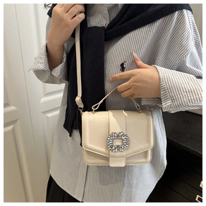 Detail of cream crossbody square bag with rhinestone buckle and adjustable strap