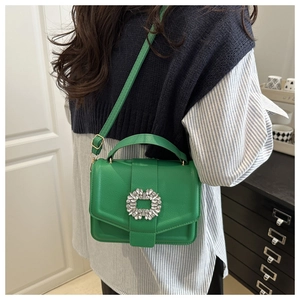 Close-up of vibrant green lychee leather handbag featuring a sparkling rhinestone buckle