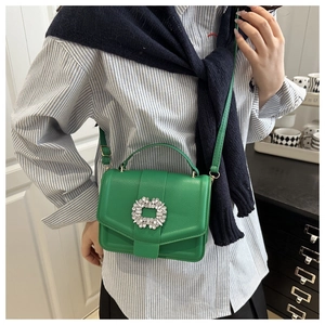 Close-up of bright green lychee leather handbag with square rhinestone buckle on a model