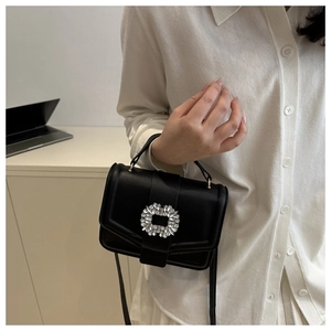 Detail shot of black pebbled leather handbag with sparkling rhinestone square buckle clasp