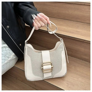 Détail du sac beige avec surpiqûres en cuir et une boucle dorée élégante