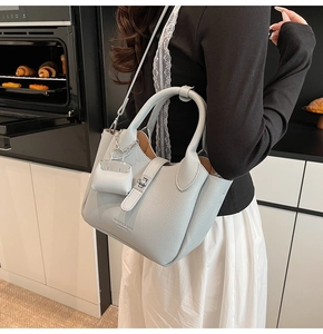 Detail van lichtblauwe emmer tas van leer met lychee-patroon en zilveren draaisluiting