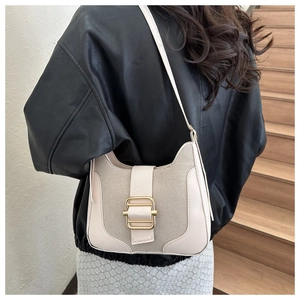 Détail du sac beige avec empiècements en cuir et boucle dorée porté par un modèle