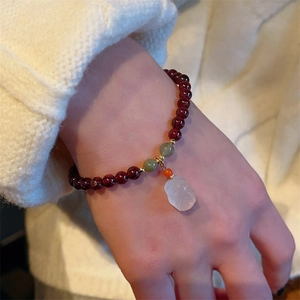 Bracciale di granato con ciondolo di giada indossato con maglione beige morbido