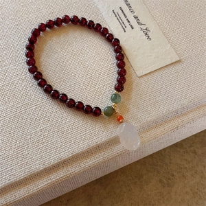Dettaglio del bracciale con perle di granato e ciondolo a forma di coniglio in giada