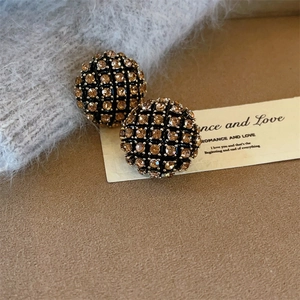 Gros plan sur des boucles d'oreilles hémisphères avec grille noire et strass champagne